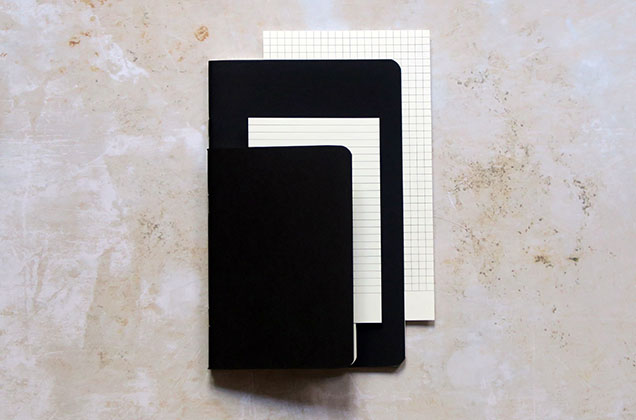 Cahier noir A5 ouvert sur un bureau – pages vierges visibles